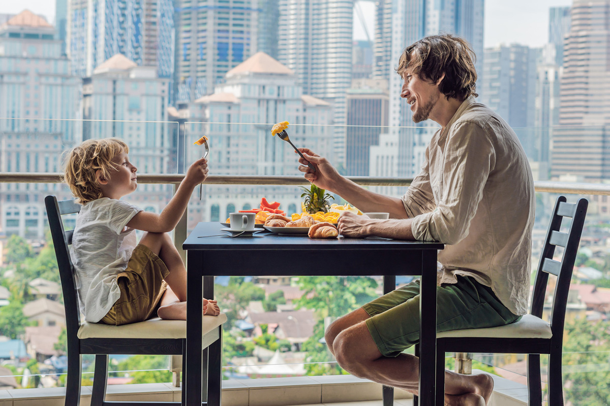 Father and son on balcony eating 1200x800px